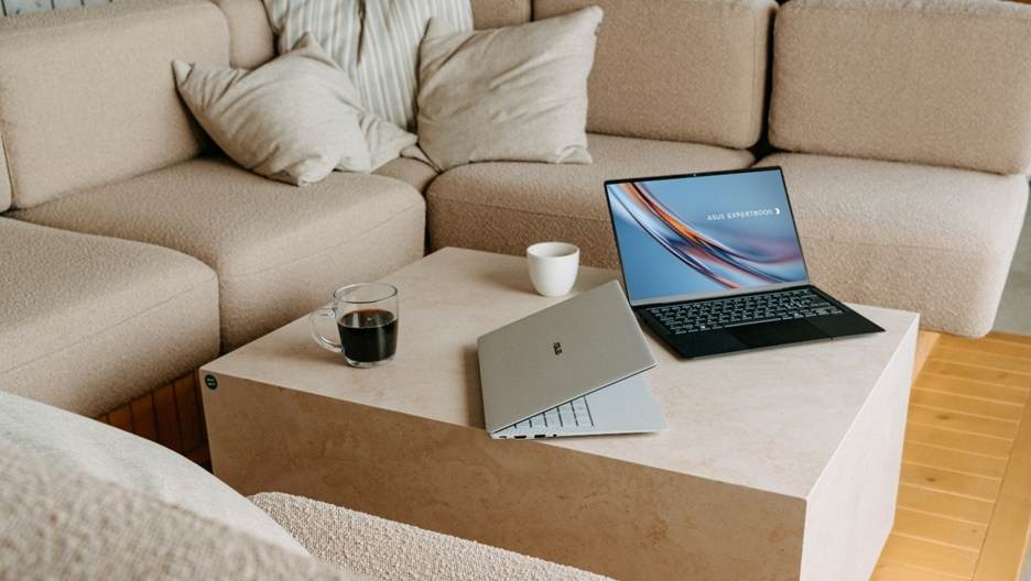 A person is sitting on a couch, working on a laptop and a tablet, with a mug and a cup on the table.
AI-generated content may be incorrect.